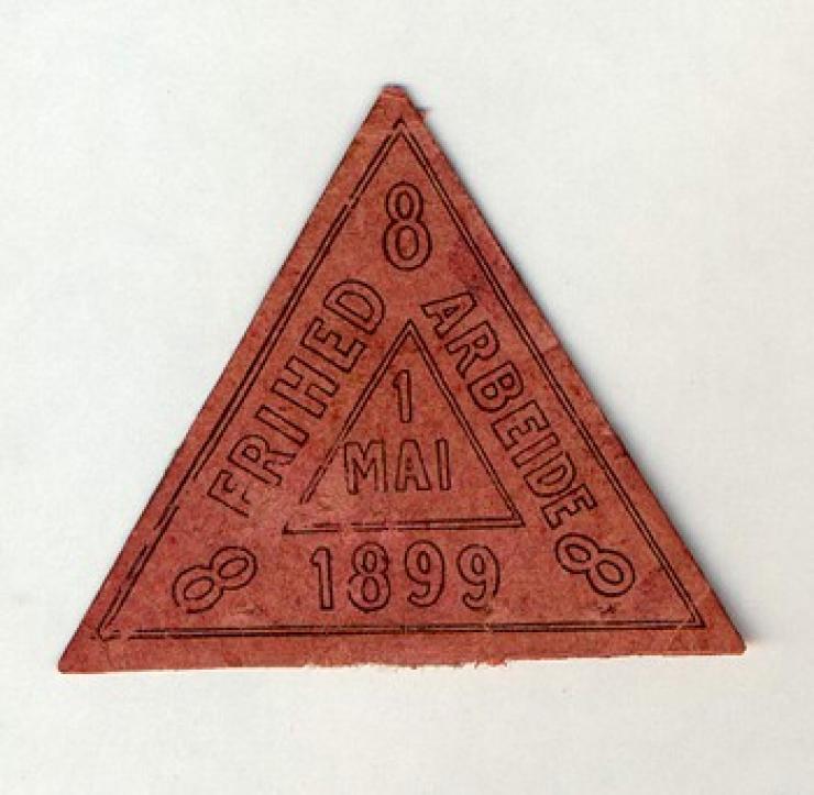 Billedet er fra Arbejdermuseet og viser et mærke fra 1899, der viser kravet om otte timers arbejde.