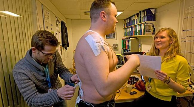 Bagageportør Christoffer Nyland får monteret elektroder på kroppen af Phd-studerende Henrik Koblaub og Stine Hvid Bern. På den måde måler de, hvordan arbejdet påvirker musklerne.