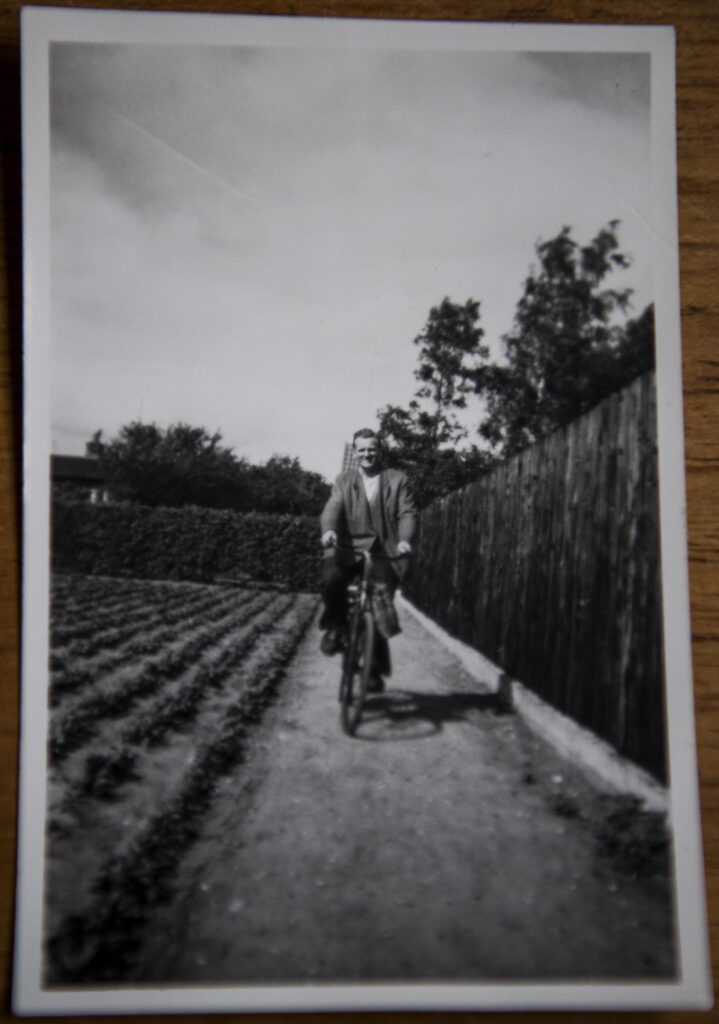 Jens Erik Frederiksen cykler langs rækkerne af grøntsager på den en halv tønde store kolonihavegrund i Ølby ved Køge, hvor han senere byggede sit eget hus. Billedet er fra 1950'erne, og plankeværket til højre står endnu.